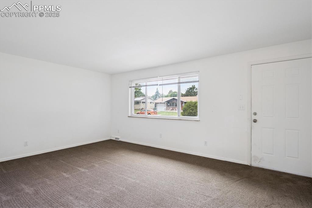 Image 2 of 19: Spare room featuring dark carpet and baseboards