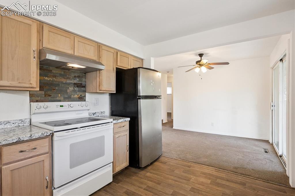 Image 5 of 19: Kitchen featuring white electric range, light brown cabinetry, and under ca