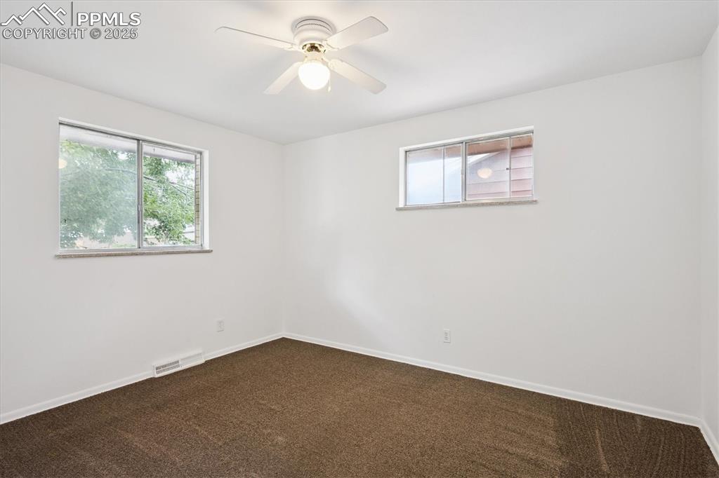 Image 7 of 19: Unfurnished room featuring dark carpet and a ceiling fan