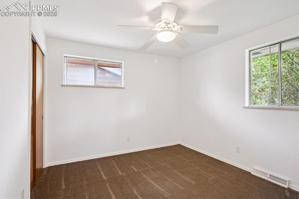Image 9 of 19: Unfurnished bedroom with a closet, dark colored carpet, a ceiling fan, and