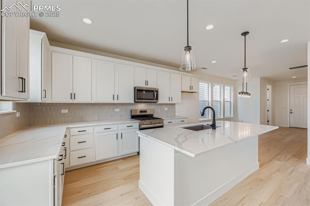 Image 10 of 28: Kitchen with stainless steel appliances, light wood-style flooring, recesse