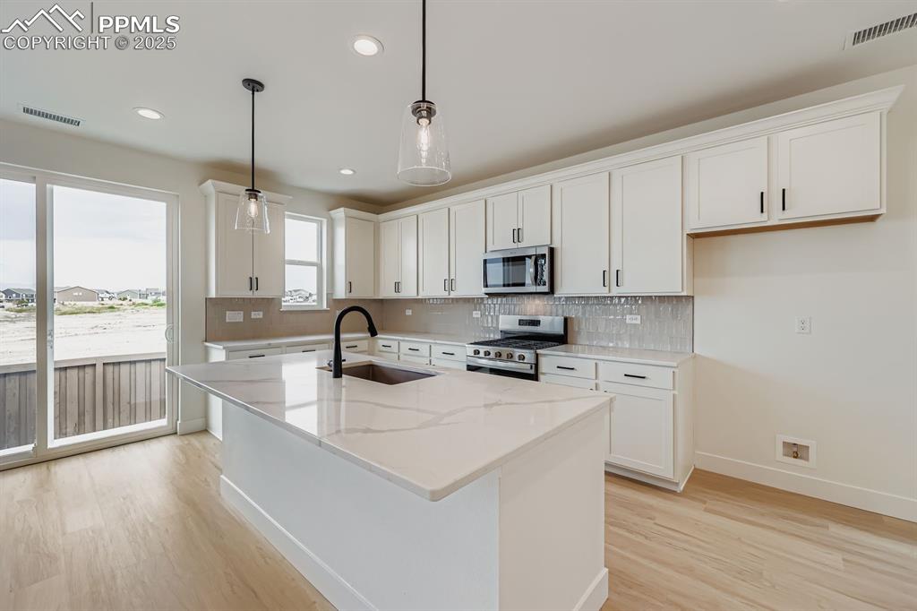 Image 11 of 28: Kitchen featuring decorative backsplash, stainless steel appliances, white 