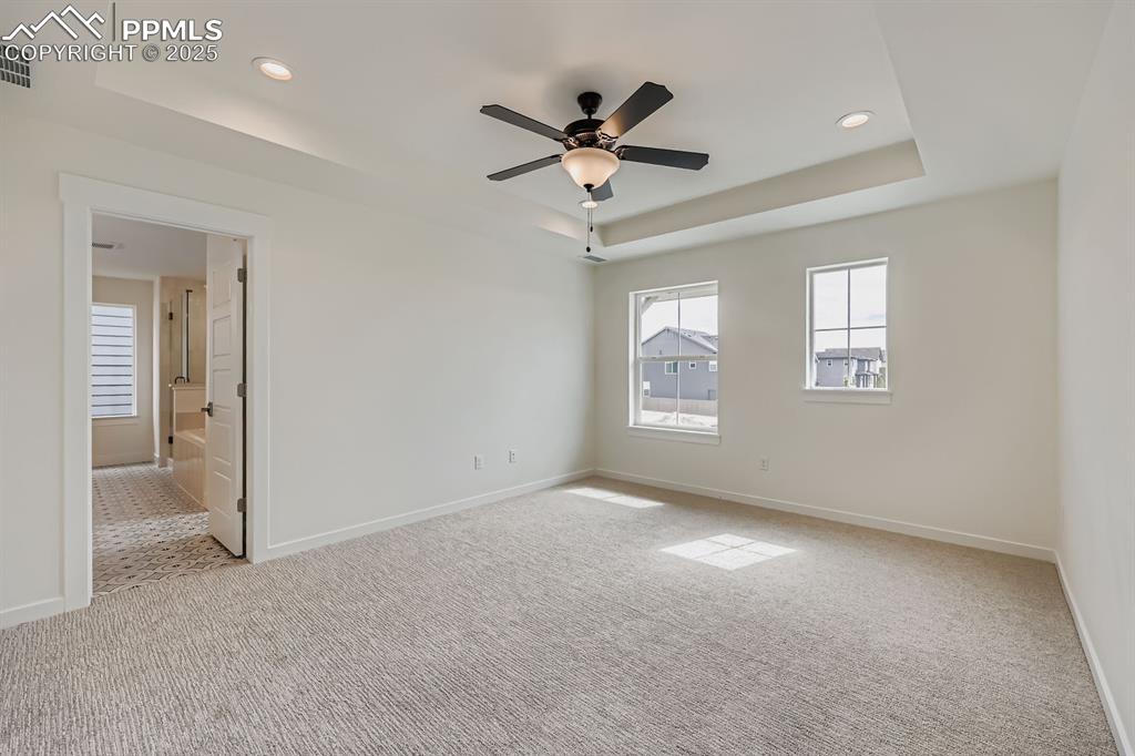 Image 15 of 28: Unfurnished room featuring a tray ceiling, light colored carpet, a ceiling 