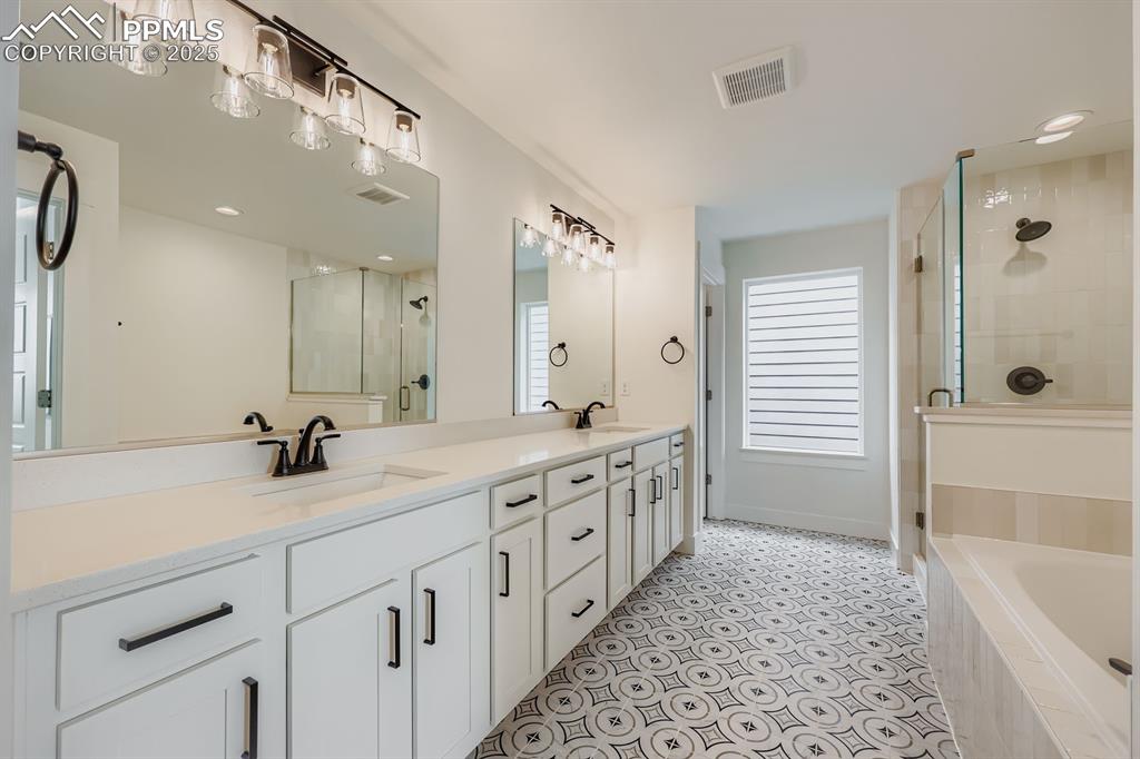 Image 17 of 28: Bathroom with a shower stall, double vanity, recessed lighting, and a bath