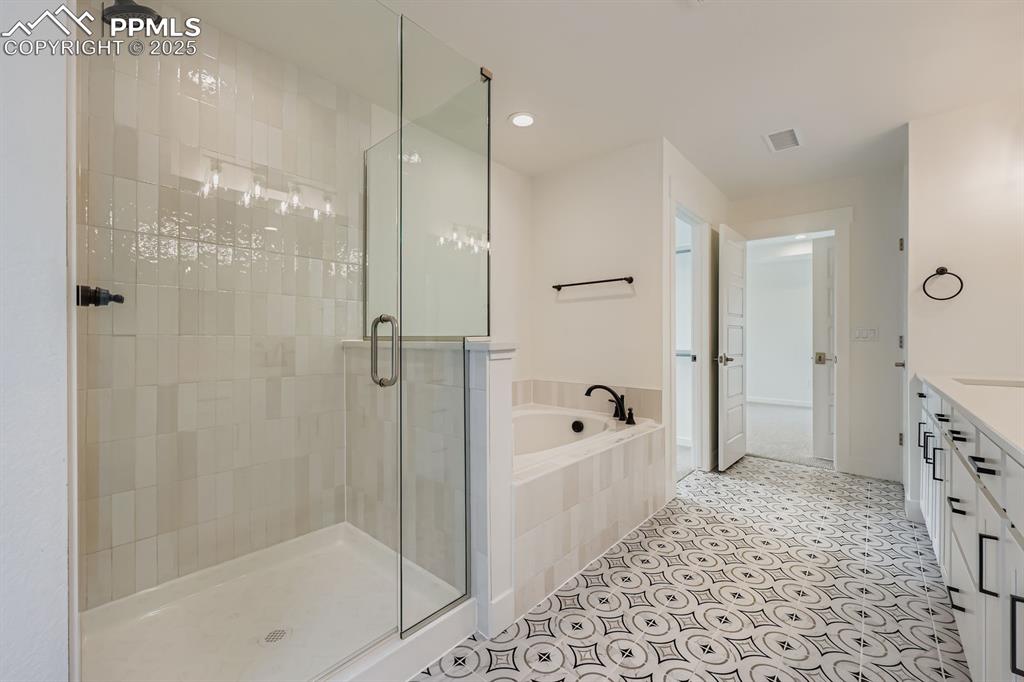 Image 18 of 28: Full bath featuring a shower stall, a garden tub, vanity, recessed lighting
