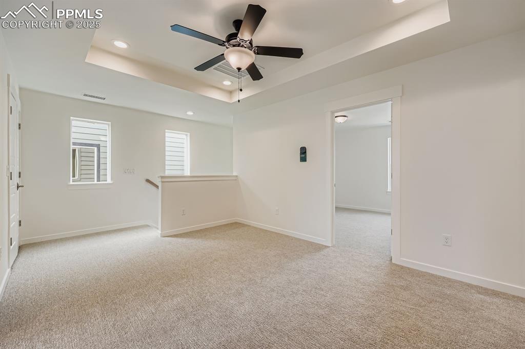 Image 25 of 28: Unfurnished room featuring a raised ceiling, recessed lighting, light carpe