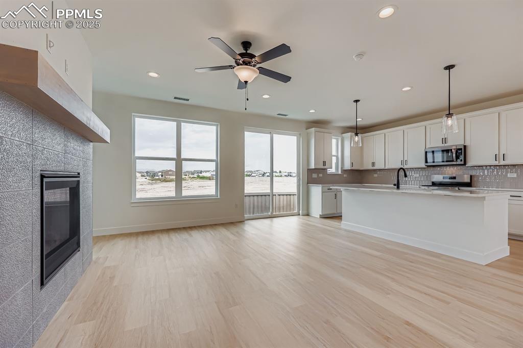 Image 6 of 28: Kitchen featuring backsplash, light countertops, a fireplace, light wood-st
