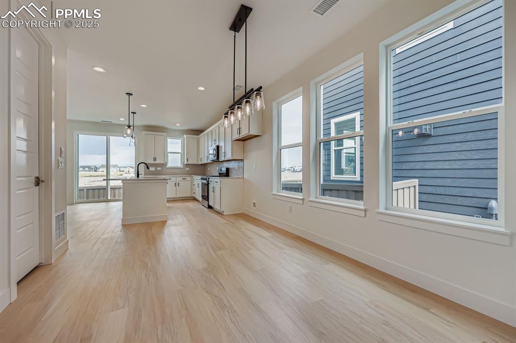 Image 9 of 28: Kitchen featuring a kitchen island with sink, light wood finished floors, s
