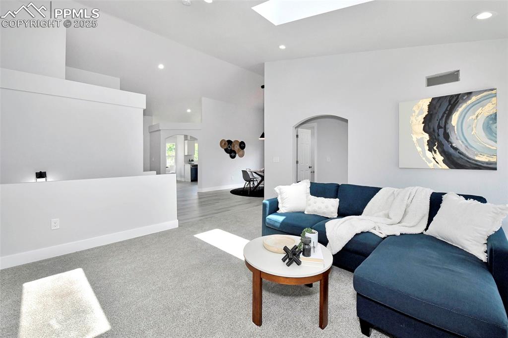 Image 11 of 44: Living room featuring vaulted ceiling, a skylight, light colored carpet, re
