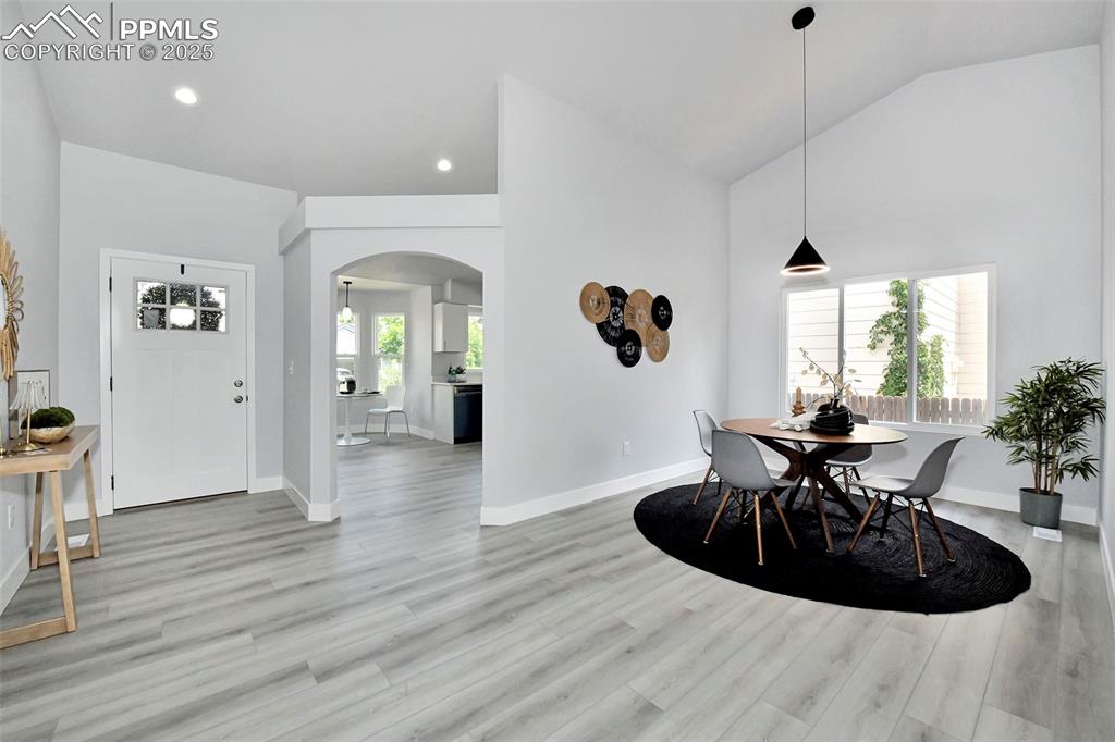 Image 17 of 44: Dining room with arched walkways, light wood-style flooring, high vaulted c