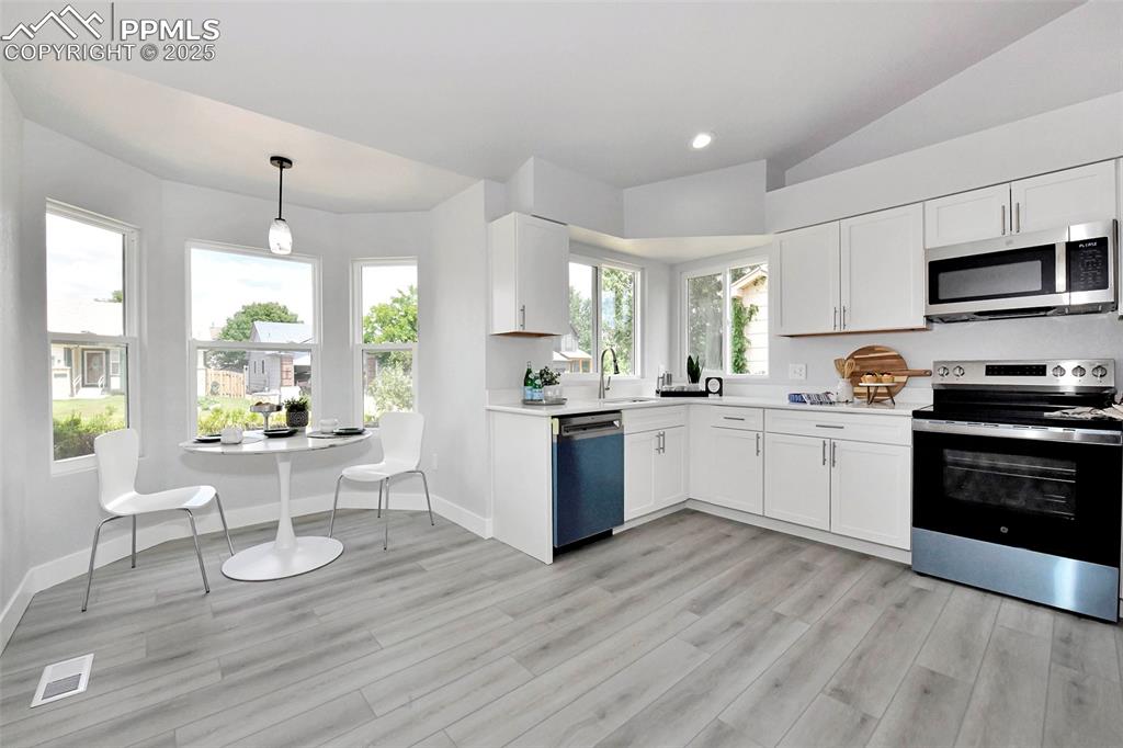 Image 2 of 44: Kitchen with appliances with stainless steel finishes, lofted ceiling, ligh