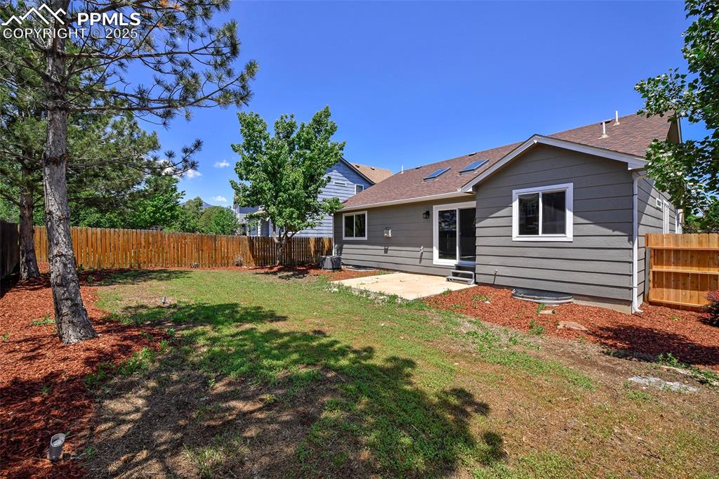 Image 22 of 44: Rear view of house with roof with shingles, a fenced backyard, and a patio