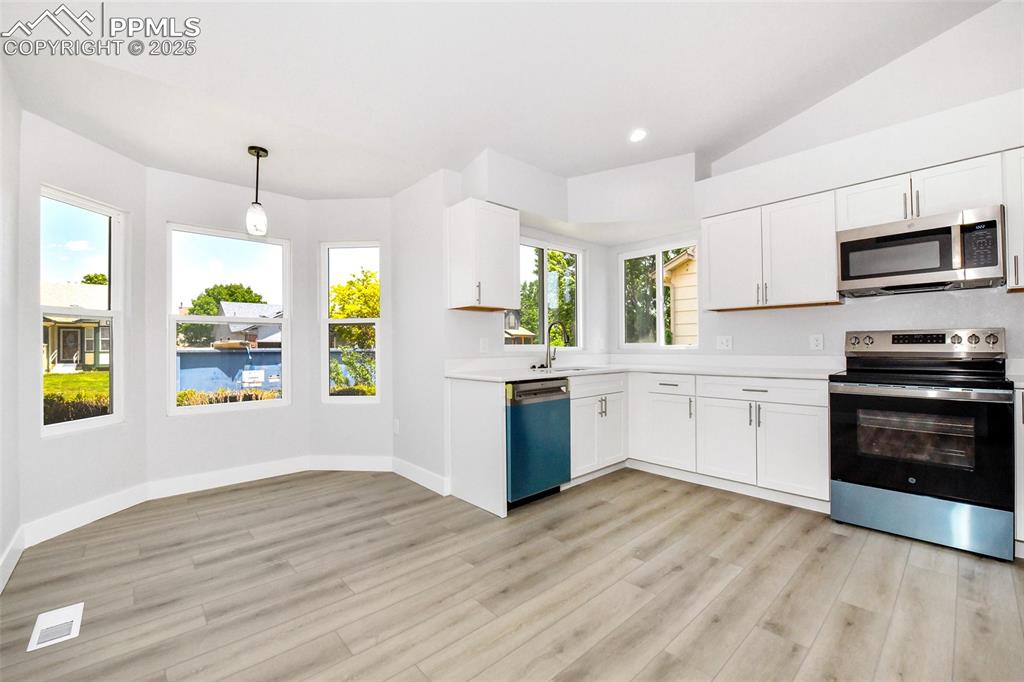 Image 25 of 44: Kitchen featuring appliances with stainless steel finishes, vaulted ceiling