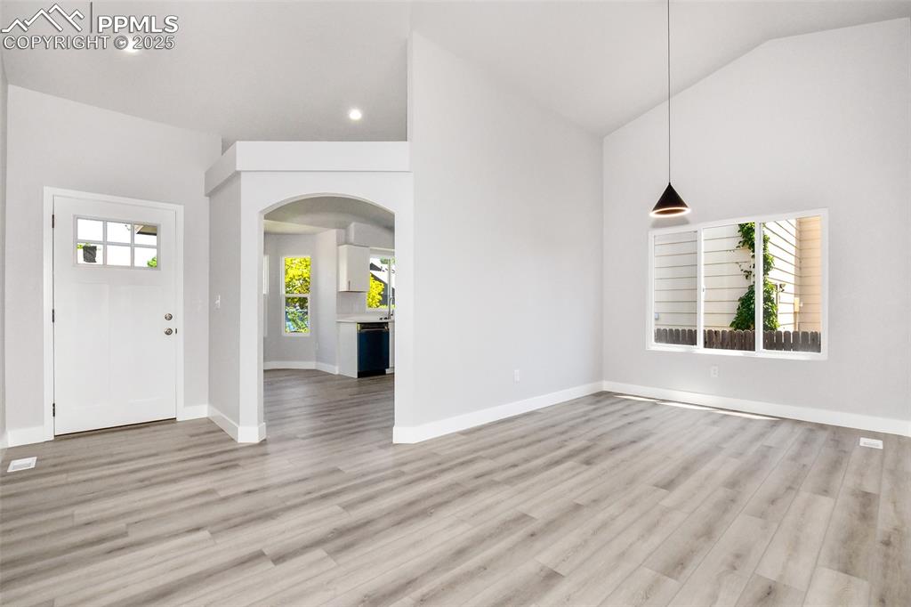 Image 27 of 44: Foyer with arched walkways, light wood-style flooring, and vaulted ceiling