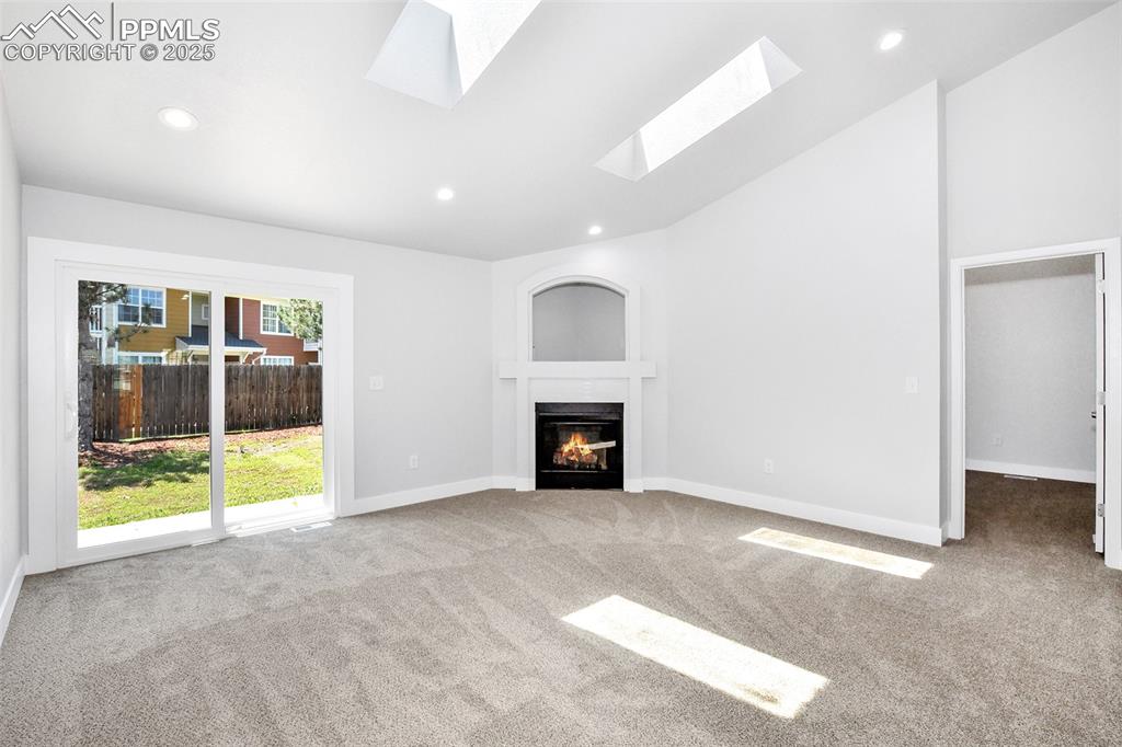 Image 29 of 44: Unfurnished living room featuring carpet flooring, a glass covered fireplac