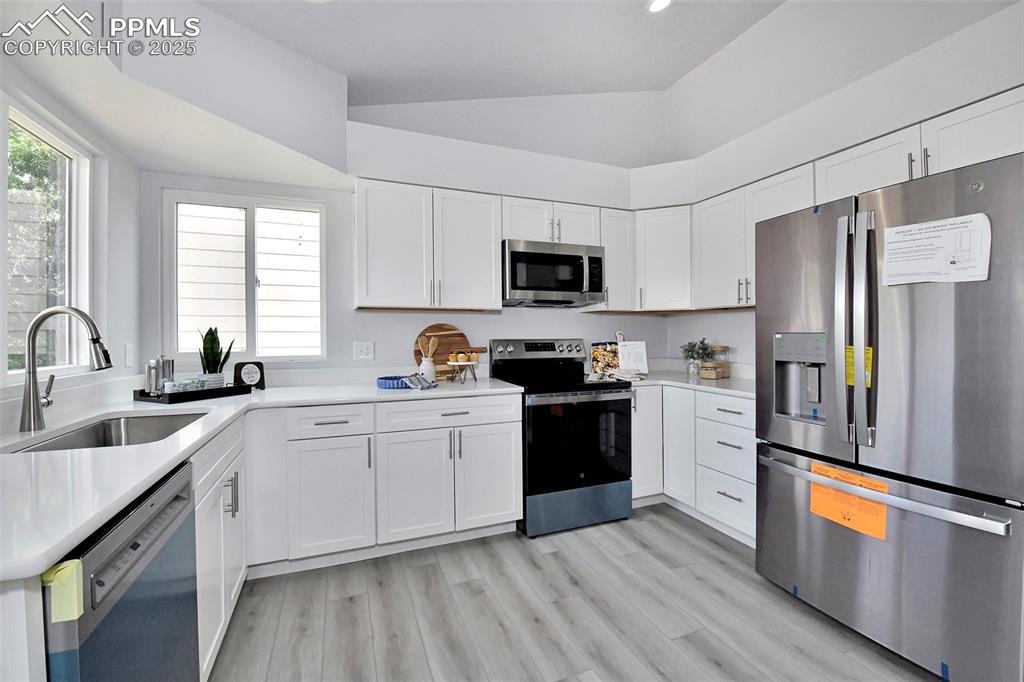 Image 3 of 44: Kitchen with appliances with stainless steel finishes, light wood-style flo