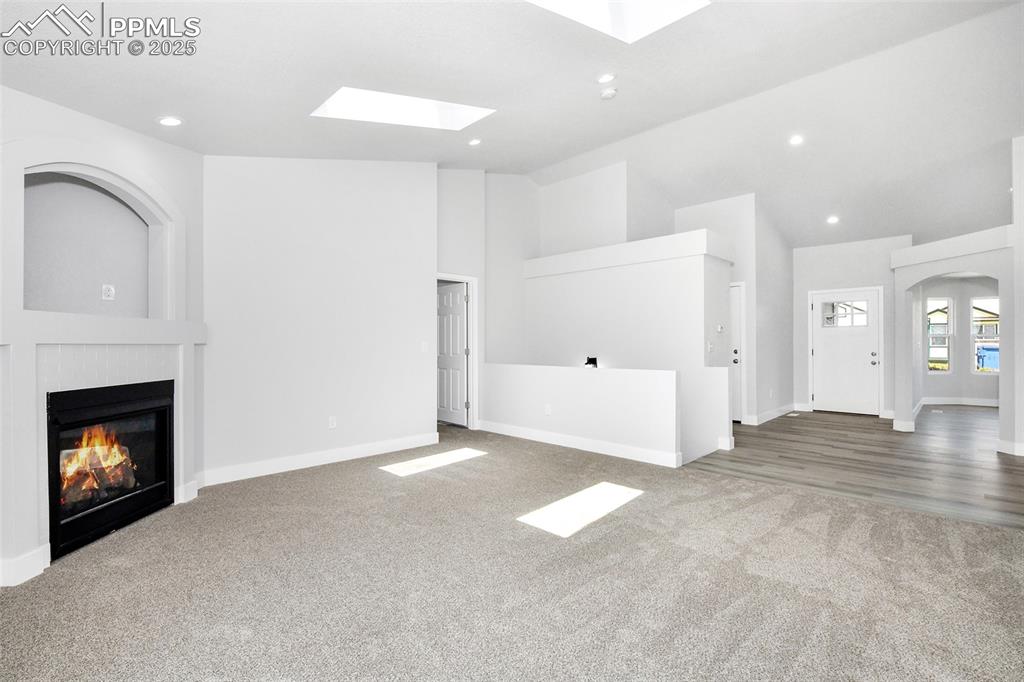 Image 31 of 44: Unfurnished living room with recessed lighting, carpet, a glass covered fir
