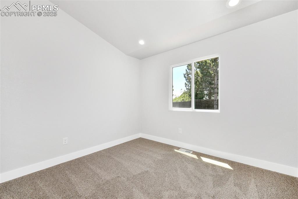 Image 33 of 44: Carpeted empty room featuring lofted ceiling and recessed lighting