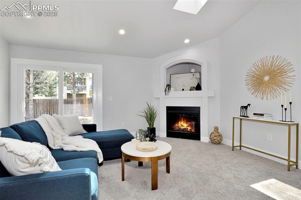 Image 6 of 44: Carpeted living area with a glass covered fireplace, a skylight, and recess