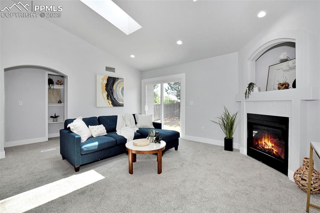 Image 7 of 44: Carpeted living room featuring vaulted ceiling, a skylight, a glass covered