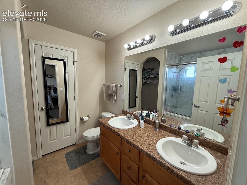 Image 12 of 16: Dual vanity with wood-finish cabinetry, built-in mirror, and laminate count
