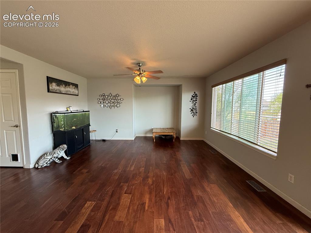 Image 3 of 16: Spacious interior featuring rich wood-finish flooring, a ceiling fan, and a