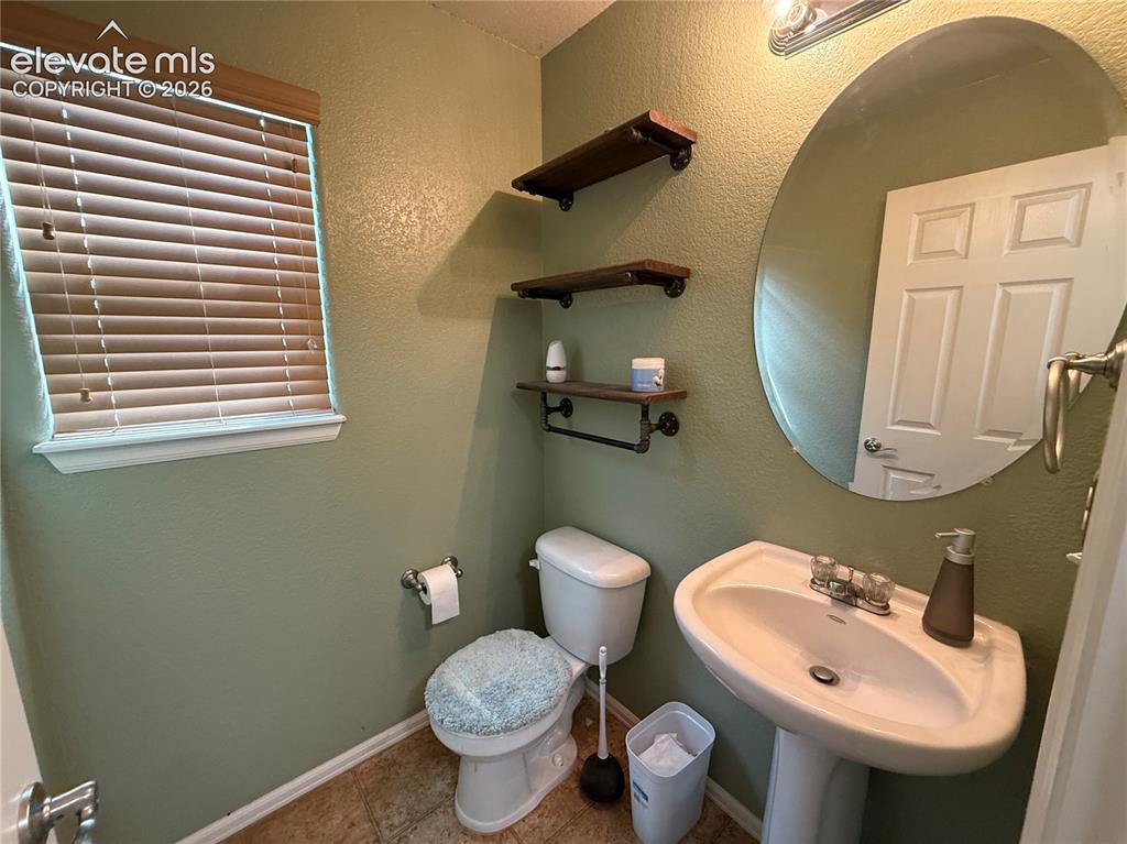 Image 7 of 16: Pedestal sink with chrome fixtures, oval mirror, and wood-finish shelving w