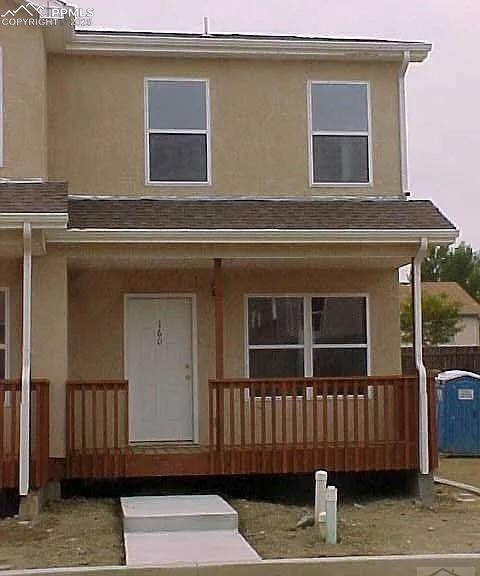 Caption: View of front of house featuring stucco siding and covered porch