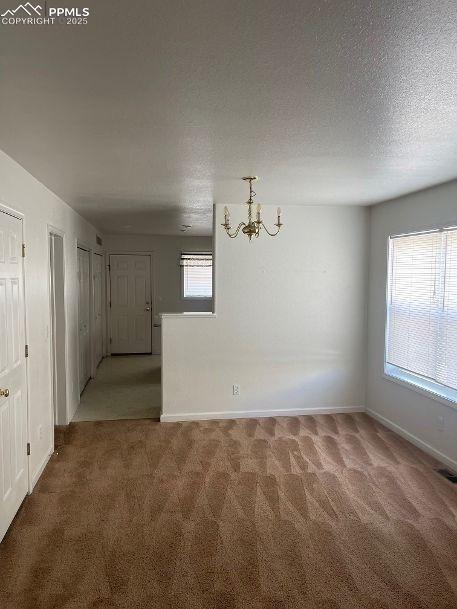Image 3 of 5: Unfurnished dining area featuring carpet flooring, a textured ceiling, and