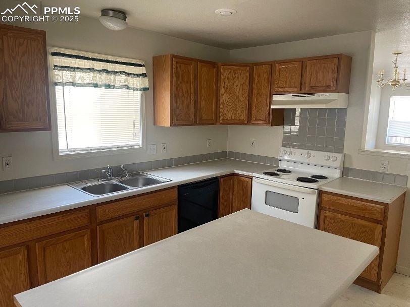 Image 4 of 5: Kitchen with brown cabinets, white range with electric cooktop, and light c