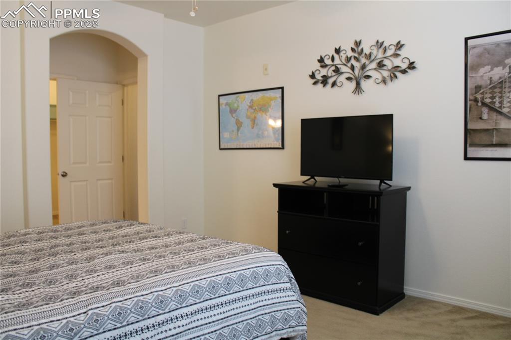 Image 13 of 20: Bedroom featuring arched walkways and light colored carpet