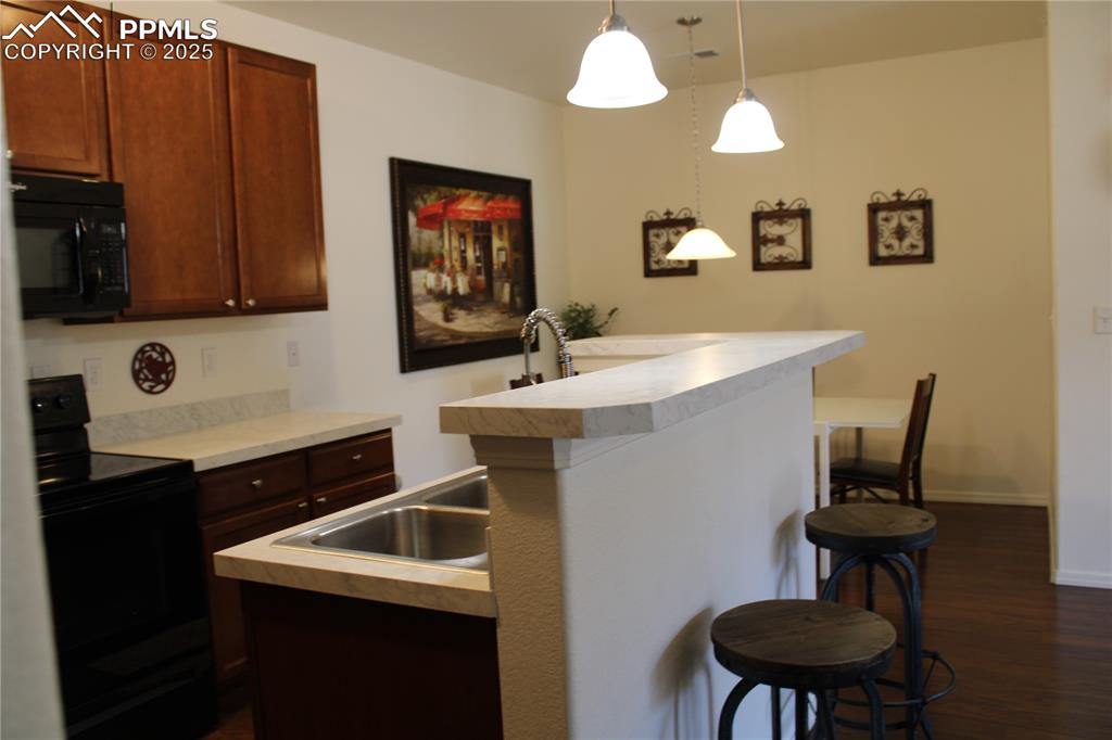 Image 8 of 20: Kitchen with black appliances, a kitchen breakfast bar, a kitchen island wi