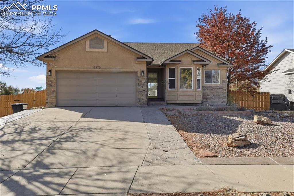 Caption: View of front facade with driveway, stone siding, roof with shingles, and an attached garage