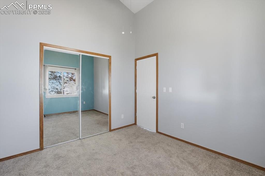 Image 18 of 43: Unfurnished bedroom featuring carpet, a high ceiling, and a closet