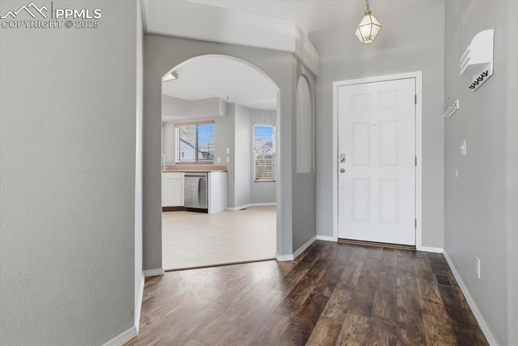 Image 21 of 43: Entrance foyer featuring arched walkways and dark wood finished floors