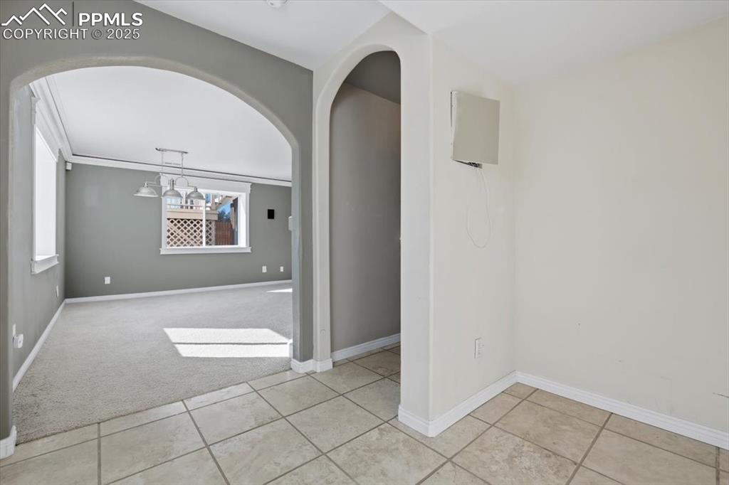 Image 24 of 43: Spare room with light carpet, light tile patterned floors, and arched walkw