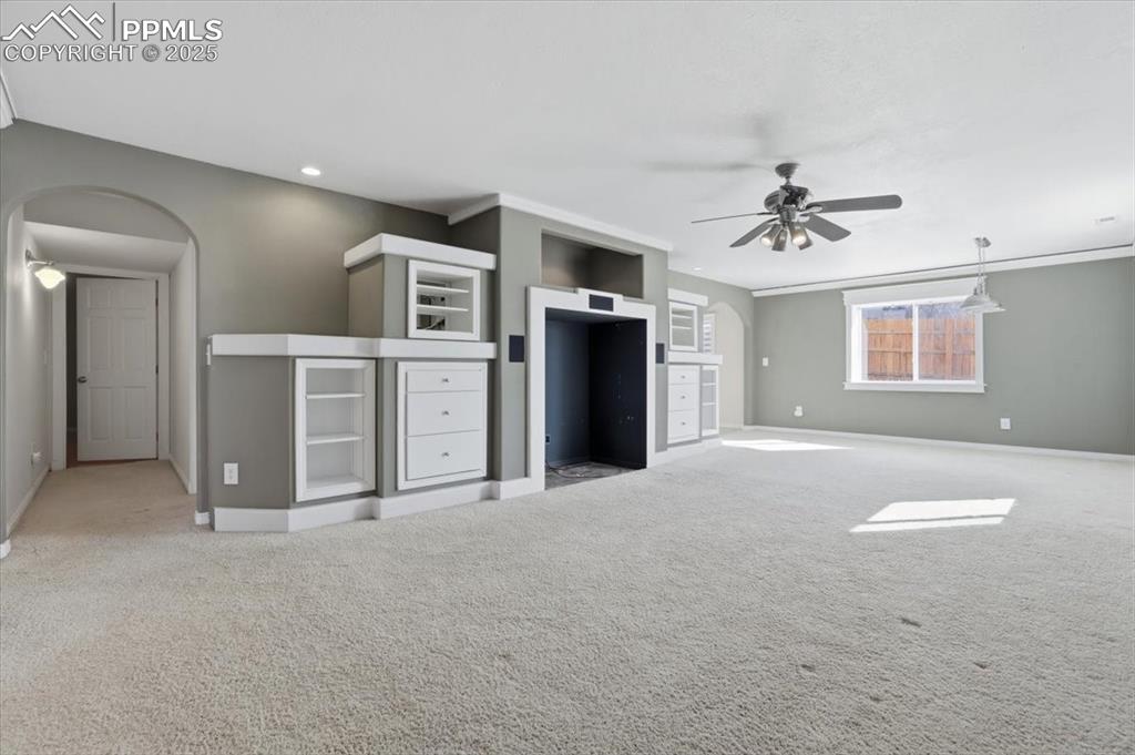 Image 28 of 43: Unfurnished living room featuring arched walkways, light colored carpet, an