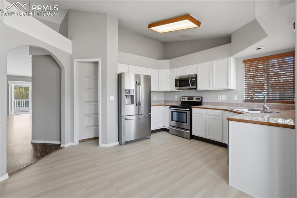 Image 3 of 43: Kitchen featuring arched walkways, appliances with stainless steel finishes