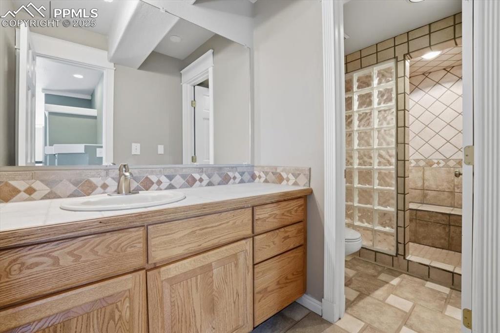 Image 30 of 43: Bathroom with vanity, a shower stall, and backsplash