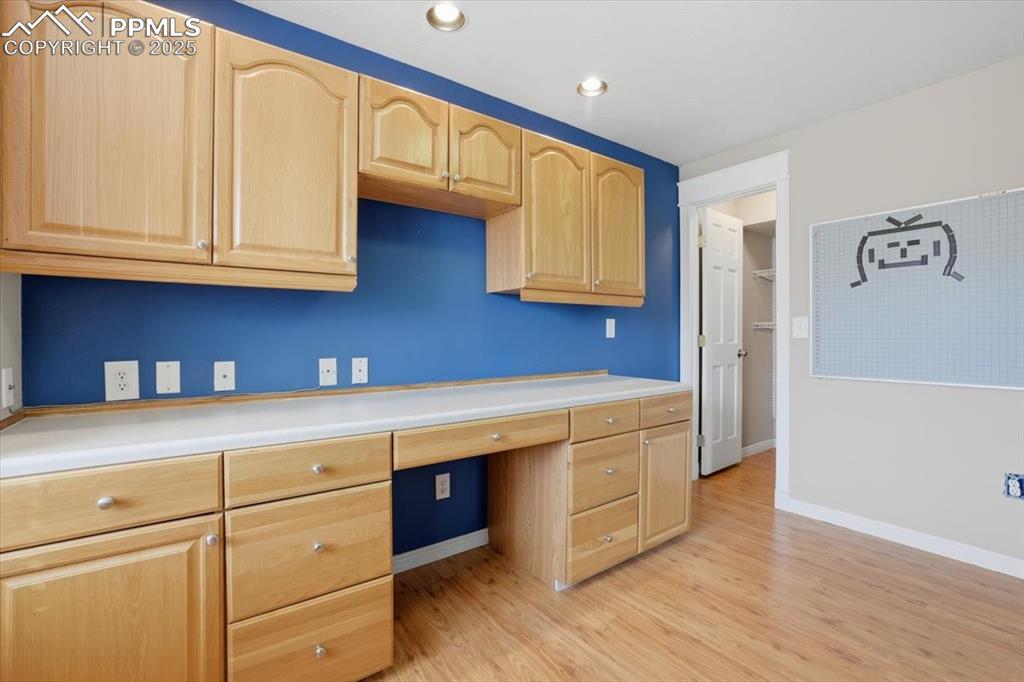 Image 39 of 43: Unfurnished office featuring built in desk, light wood-style flooring, and 