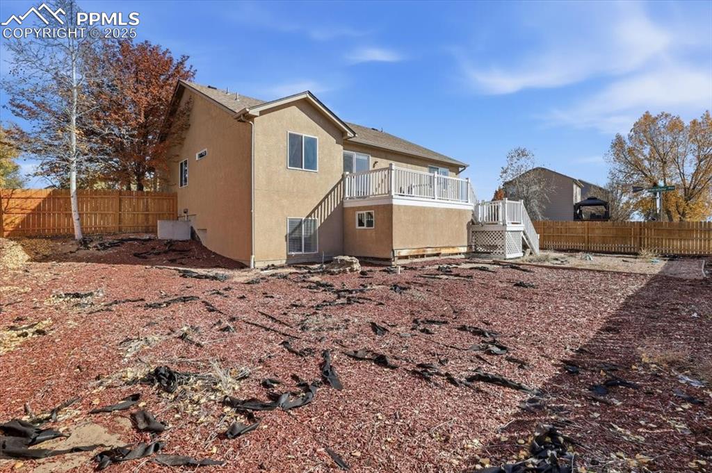 Image 43 of 43: Back of property with stairs, stucco siding, and a deck