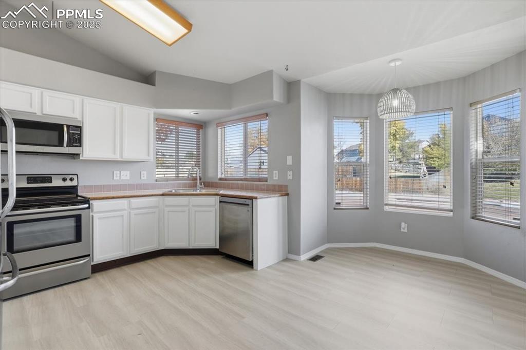Image 7 of 43: Kitchen featuring stainless steel appliances, pendant lighting, light wood 