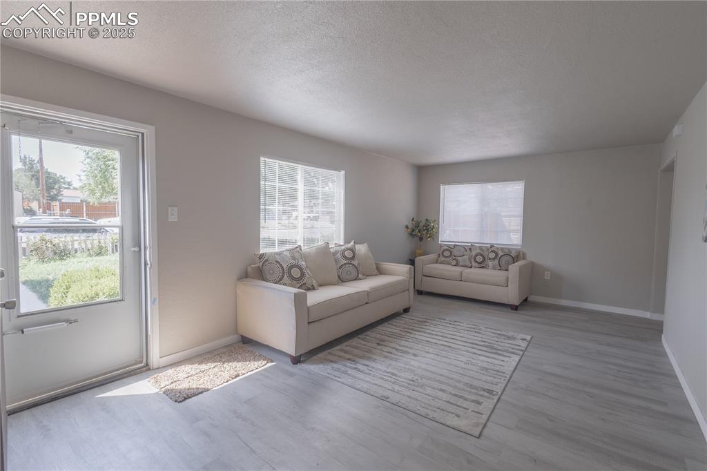 Image 3 of 21: Living area with a textured ceiling, wood finished floors, and plenty of na