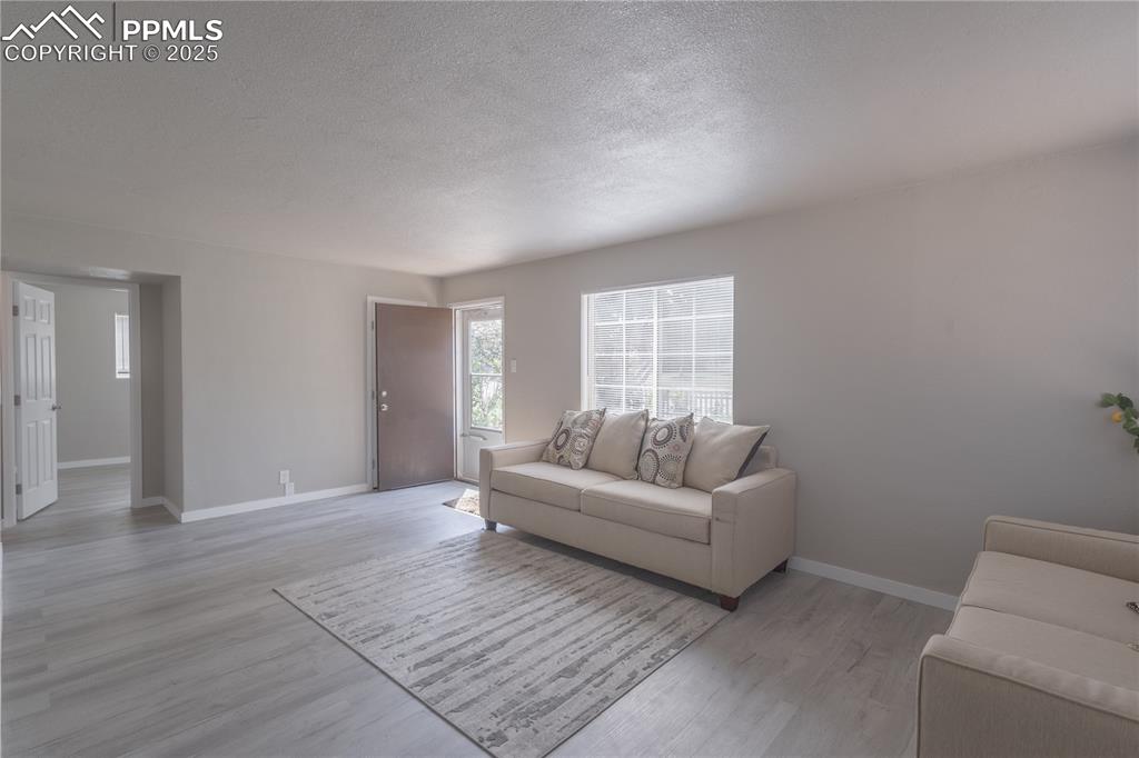 Image 4 of 21: Living area featuring light wood-type flooring and a textured ceiling