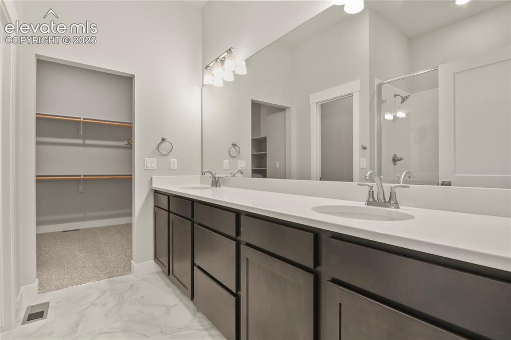 Image 14 of 50: En-suite bath with dual sinks, quartz counter, and walk in closet