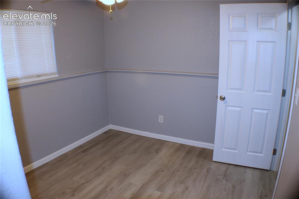 Image 21 of 28: Wood-finish flooring, white trim, and a white six-panel door
