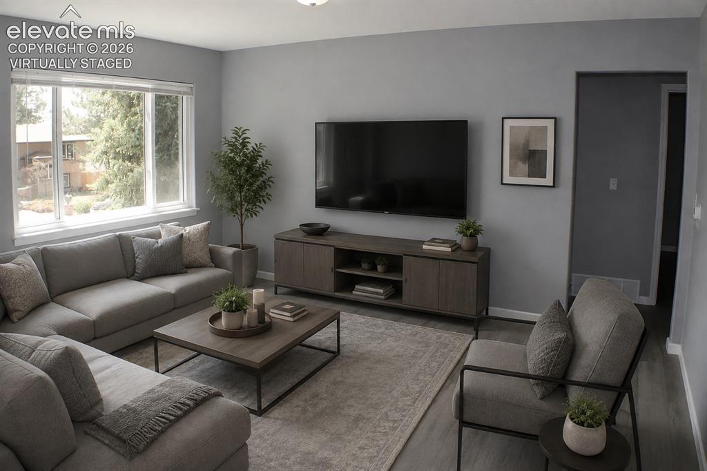 Image 5 of 28: Spacious living area featuring large windows, wood-finish flooring, and lig