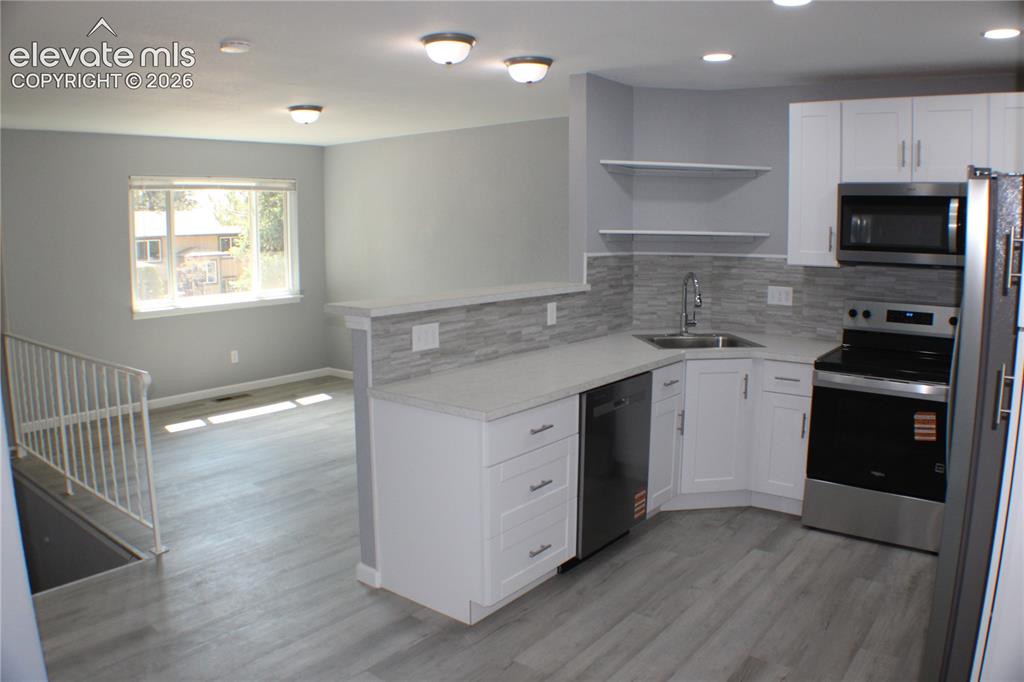 Image 8 of 28: Kitchen featuring white cabinetry, light-toned countertops, a stainless ste