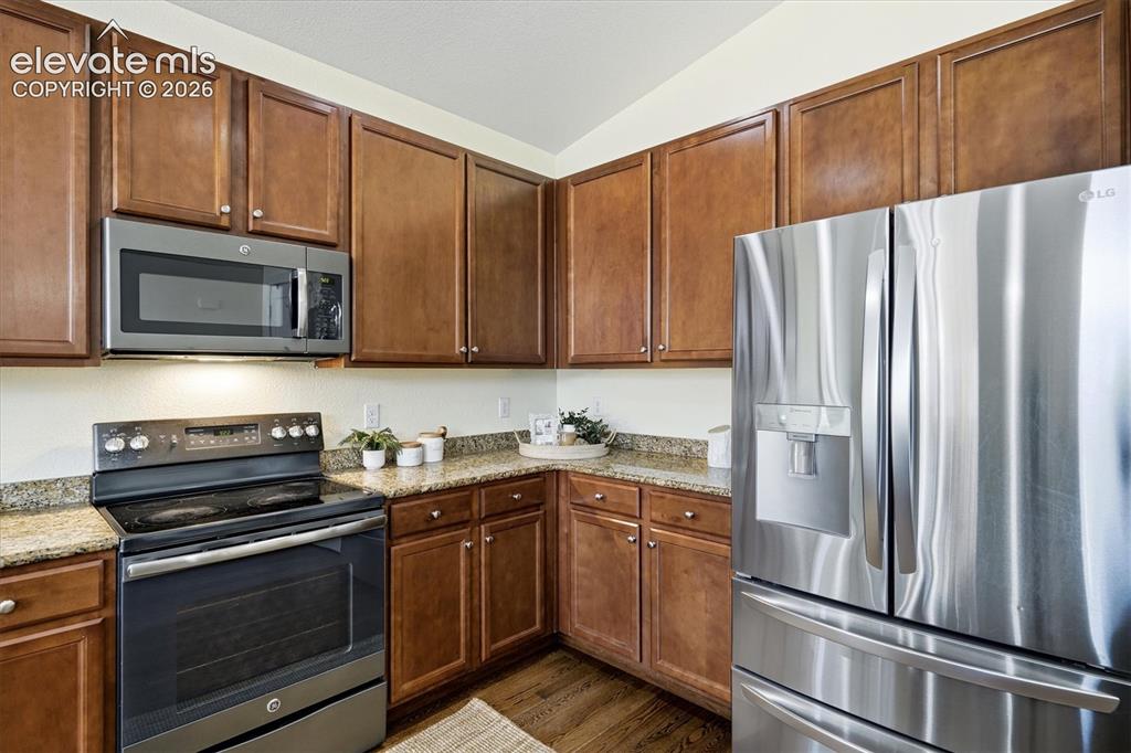 Image 11 of 45: Warm wood cabinetry and stainless steel appliances anchor this well-appoint