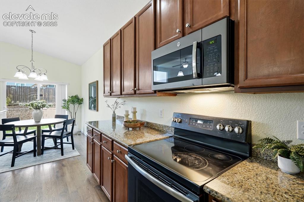 Image 12 of 45: Kitchen featuring wood-finish cabinetry, granite countertops, and stainless